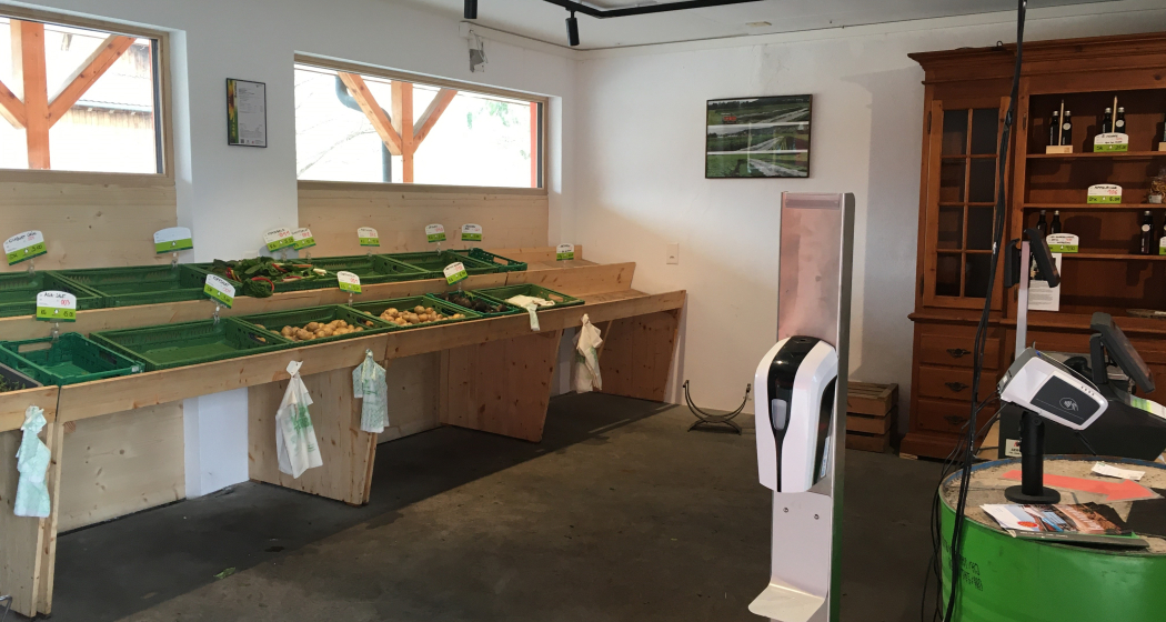 Selbstbedienungsbereich des Birkahoflädile mit leeren Verkaufstischen und grüner Kasse – nachhaltiger Hofverkauf in Liechtenstein.